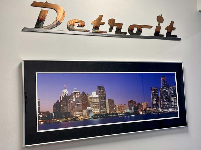 Photo Of Metal Detroit Letters On Wall Above Framed Photo Of City Skyline