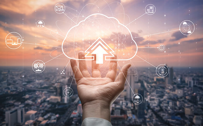 Photo of a hand holding an illustrated cloud network with a city skyline in background